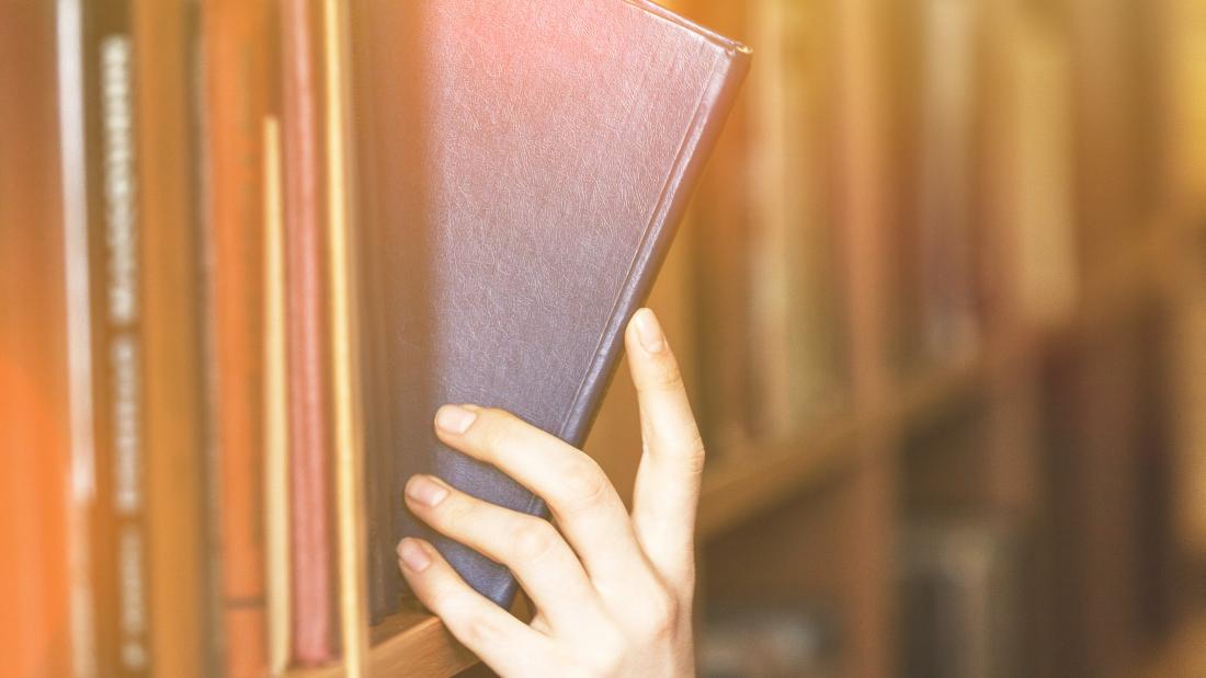 Student taking a book off a shelf.