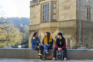 Students sitting in front of Bangor University's Memorial Arch
